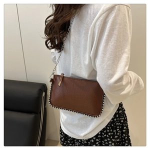 Detail of brown crocodile pattern shoulder bag with silver chain and bead trim