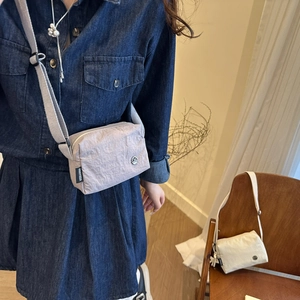 Dettaglio di una borsa a tracolla leggera in nylon a pieghe con stemma in metallo M