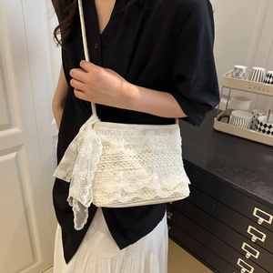 Elegant white lace ruffled shoulder bag with side bow detail worn by a model in a room