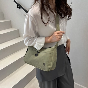Close-up of light green nylon tote bag with metal buckle on a white model outfit