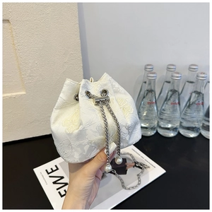 Détail du sac seau en dentelle blanche avec texture florale 3D et cordon perlé