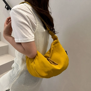 Gele halfmaanvormige schoudertas van nylon met brede riem gedragen door een model