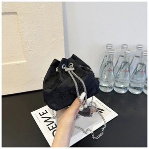 Détail du sac seau en jacquard noir avec chaîne argentée et accents de perles sur cordon
