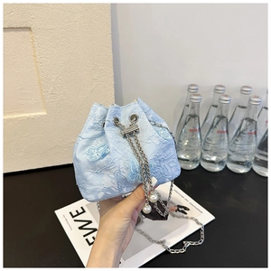 Détail du sac seau en dentelle florale bleu clair avec cordon perlé et chaîne en métal
