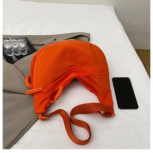 Detail of a bright orange crescent crossbody bag made of durable nylon with zipper details