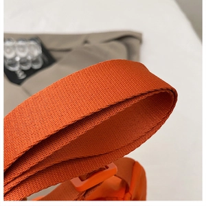 Close-up of bright orange nylon crossbody bag strap with durable twill weave texture