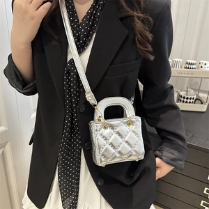 Silver quilted mini handbag with metallic finish and circular handles on a fashion model