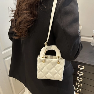 Mini white quilted crossbody bag with top handle and gold hardware on a model