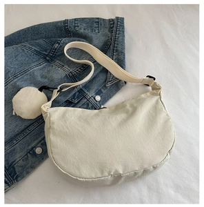Detail of off-white half-moon canvas bag with adjustable strap and mini round pouch