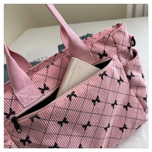 Dettaglio della borsa a tracolla in velluto rosa con motivi a fiocco nero e texture