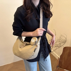 Detail of khaki nylon crescent bag with beige woven strap and matching coin purse charm
