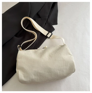 Detail of minimalist cream nylon crossbody bag with wide strap and black adjustable buckle