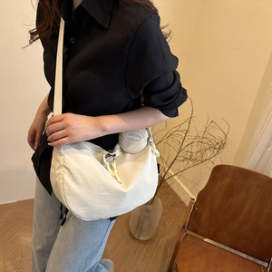 Detail of a creamy white crescent canvas crossbody bag with wide strap and coin pouch