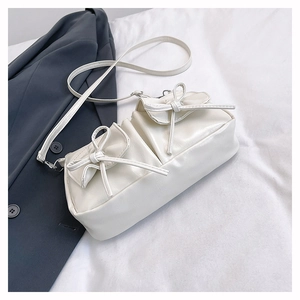 Detail of cream white crossbody bag featuring elegant 3D bows and smooth leather texture