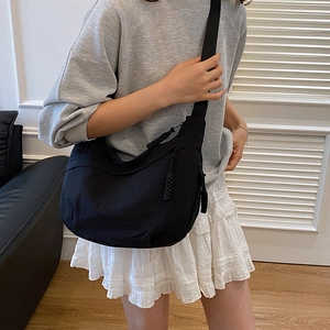 Minimalist black crescent crossbody bag with adjustable wide strap and nylon texture