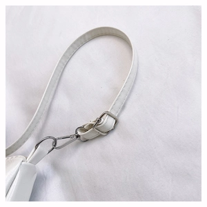 Detail view of white leather shoulder strap with silver buckle and adjustable stitching