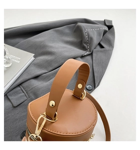Close-up of brown leather bucket bag handle with premium gold-tone metal hardware