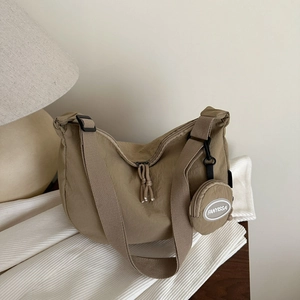 Detail of khaki crescent crossbody bag with wide strap and round detachable coin purse