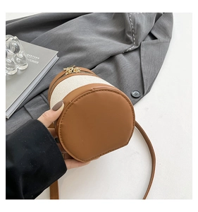 Detail of contrast stitch cylinder bucket bag with canvas and leather patchwork texture