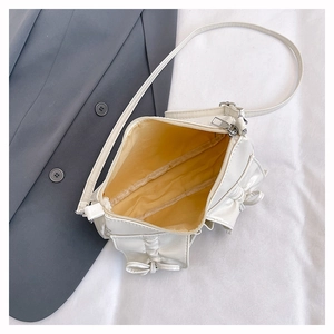 Detailed top view of a cream shoulder bag featuring a stylish bow and yellow inner lining