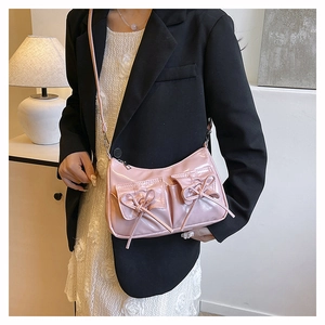 Detail of pink glossy shoulder bag with bow accents and dual flap pockets for women