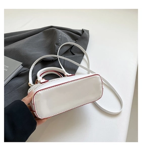Detail of white leather shell bag with red edge paint and fine woven texture