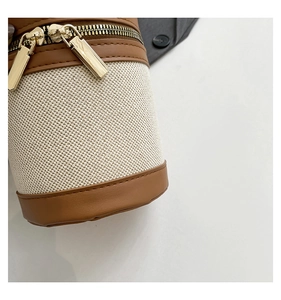 Macro detail of textured canvas and brown leather stitching on cylinder bucket bag