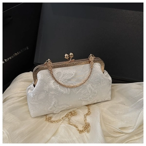 Close-up of white silk shell bag with butterfly lace embroidery and gold metal clasp