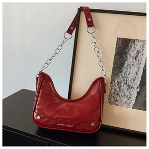 Nahaufnahme einer roten glänzenden Leder-Hobo-Tasche mit Nieten und silberner Kette