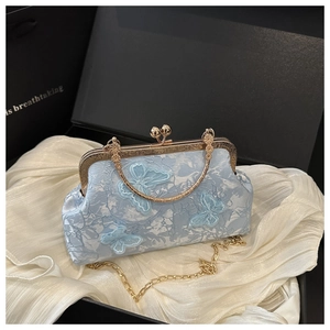 Detail of light blue shell bag with butterfly embroidery and golden metal frame handle