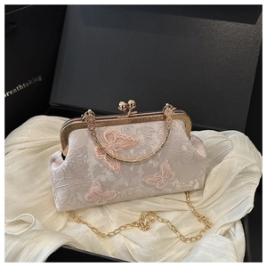 Detail of elegant shell bag featuring pink butterfly appliques and gold chain strap
