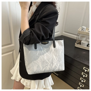 Detail of silver crinkled texture tote bag with black straps and fashion metal badge