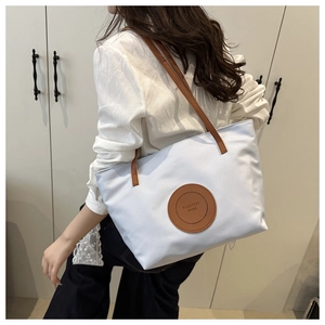 Detail of white nylon tote bag with brown leather patch and FASHION BAGS logo