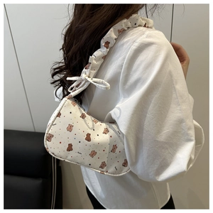 Detail of white underarm bag featuring cartoon bear print and ruffled shoulder strap