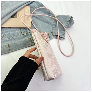Detail of pink embroidered mini crossbody bag with traditional cloud patterns and pearl buckle