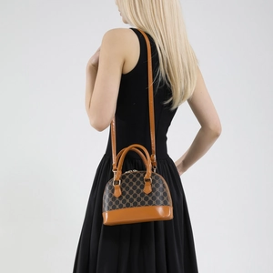 Brown monogram shell handbag with leather handles shown as a crossbody on a model