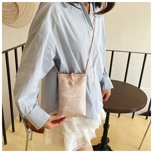 Detail of floral jacquard fabric on pink crossbody phone bag with pearl drawstring