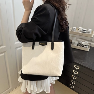 Minimalist white tote bag with crinkled paper texture and black fashion label detail