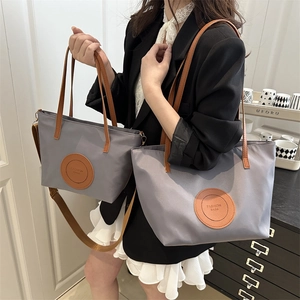 Two gray tote bags with brown leather handles and adjustable shoulder strap for summer