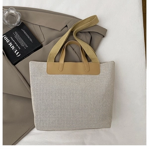 Detalle de la textura de lona y el asa de cuero marrón de un bolso tote elegante