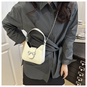 Detail of elegant cream faux leather handbag with silver bow buckle and metal chain strap