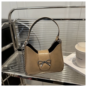 Close-up of khaki PU leather handbag with silver bow metal detail and fine chain strap