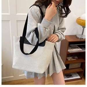 Detalle de bolso tote de lona con correas en contraste y ribete de cuero en escena minimal
