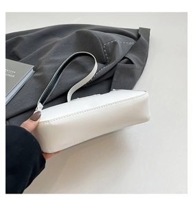 Détail du sac sous le bras blanc avec surpiqûres contrastées et bandoulière bicolore