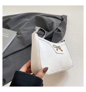 Détail du sac à bandoulière en cuir blanc avec boucle nœud doré et couture fine