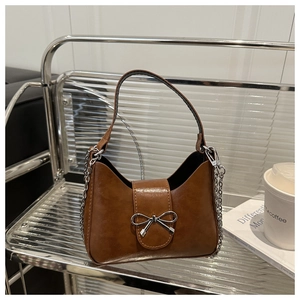 Detail of silver bow buckle and brown faux leather texture on the stylish handbag