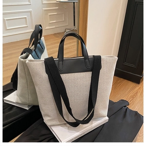 Primer plano del bolso tote de lona con contraste en cuero negro sobre un libro decorativo