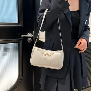 Détail du sac sous le bras demi-lune argenté avec nœud doré et pendentif fleur