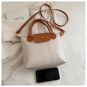 Detail of beige woven texture tote bag with brown straps and golden metal clasp