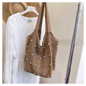 Close-up of brown woven tote bag featuring colorful beaded details and mesh texture